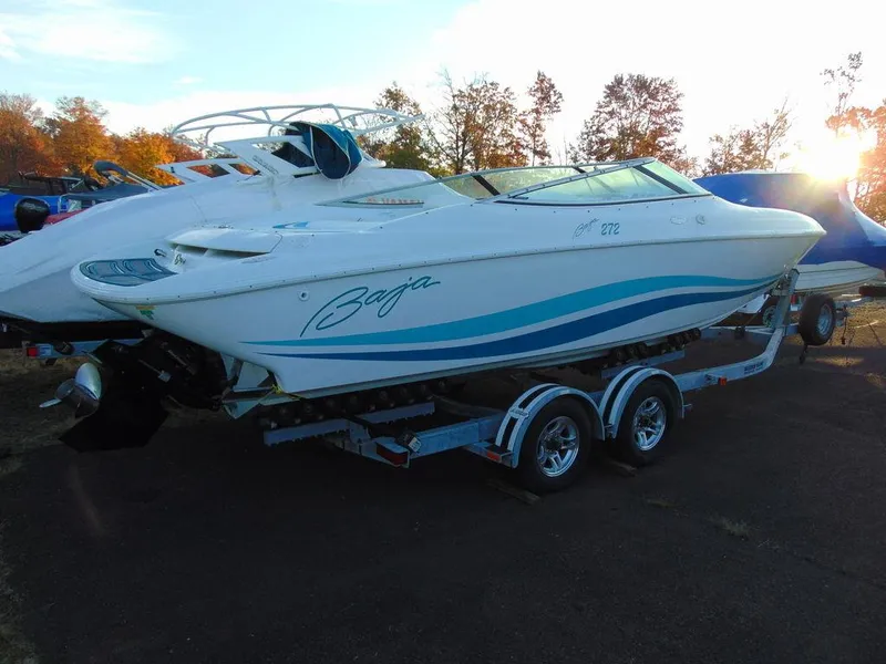 Slide: The Image of 1995 Baja 272 speedboat on trailer, white with blue accents, parked outdoors. - 3