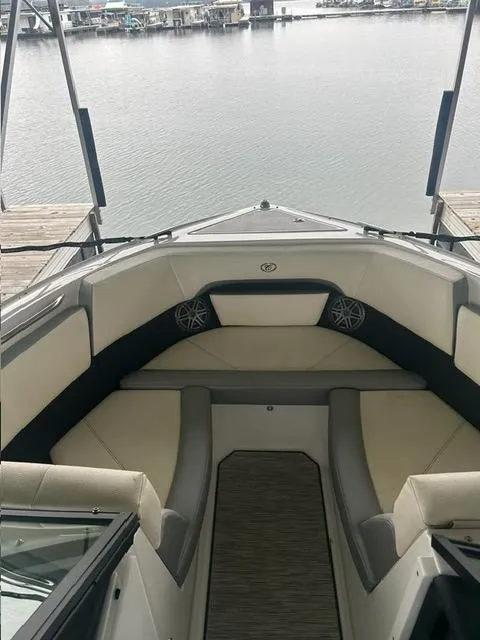 Slide: The Image of 2021 Cobalt CS23 boat interior with cushioned seating, docked by the water. - 12