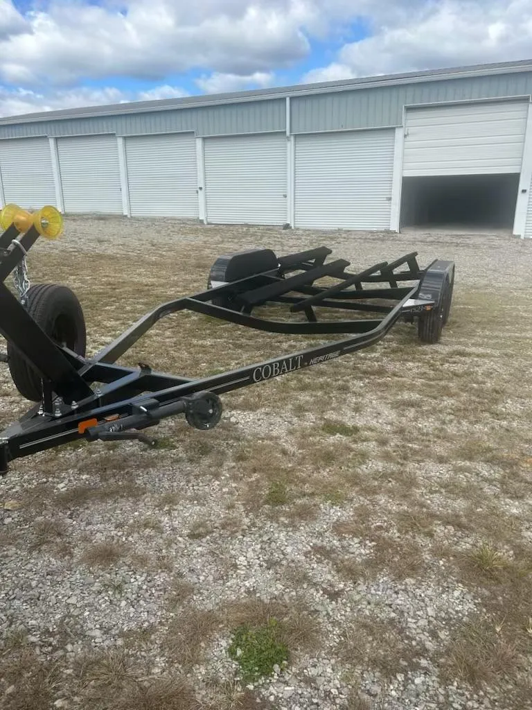Slide: The Image of 2021 Cobalt CS23 boat trailer parked on gravel near storage units. - 6