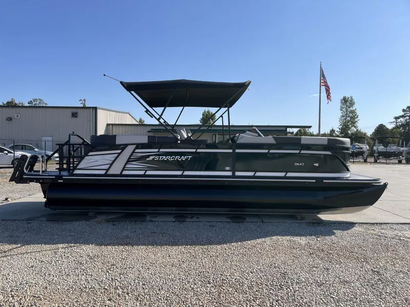 Slide: The Image of 2025 Starcraft SLS-3 pontoon boat with canopy, parked outdoors. - 3