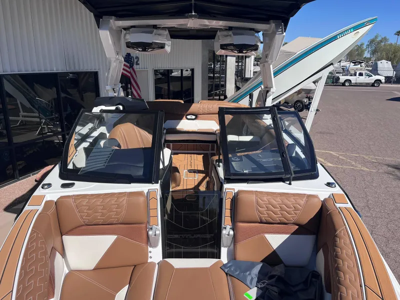 Slide: The Image of 2025 Centurion Ri245 boat interior with brown and white seating, docked outdoors. - 14