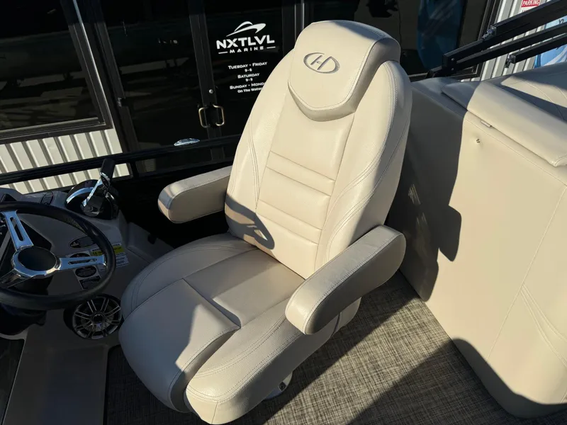 Slide: The Image of Captain's chair on 2018 Harris Solstice 240 boat, featuring beige upholstery and steering wheel. - 20