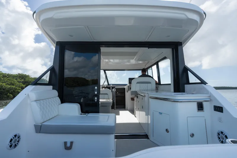 Slide: The Image of 2022 Regal 36 XO yacht interior with seating and helm, under a clear sky. - 11