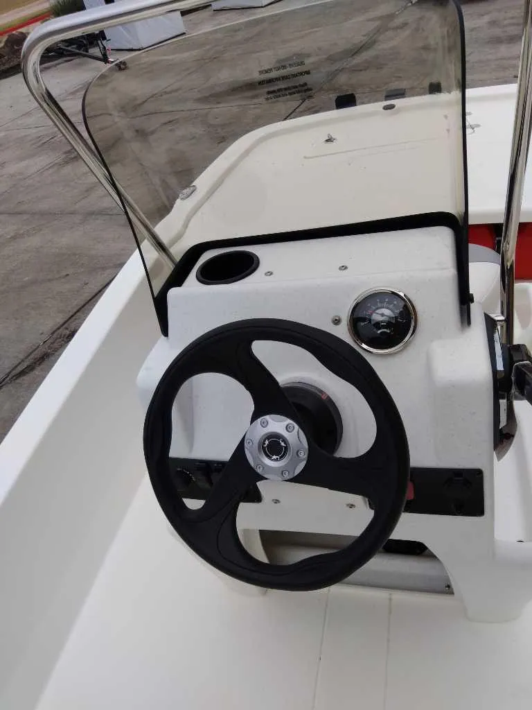 Slide: The Image of 2025 Mako Pro Skiff 13 CC boat console with steering wheel and windshield. - 2