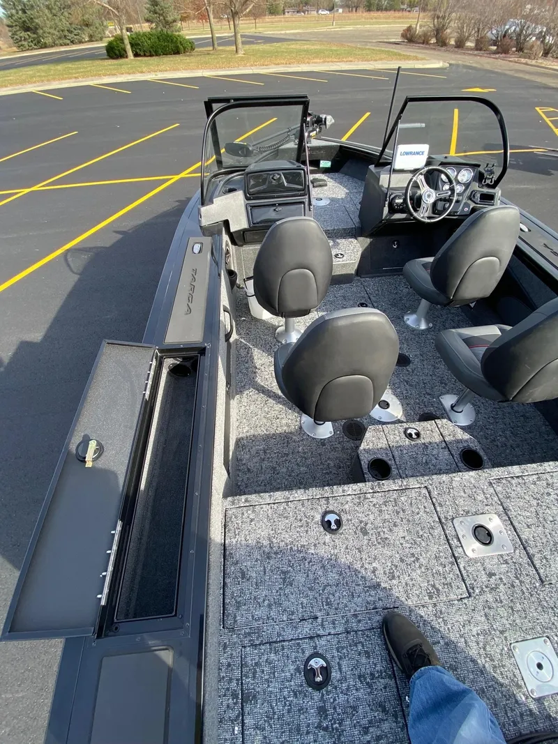 Slide: The Image of 2025 Tracker Targa V-18 WT boat interior with seating and dashboard in a parking lot. - 7