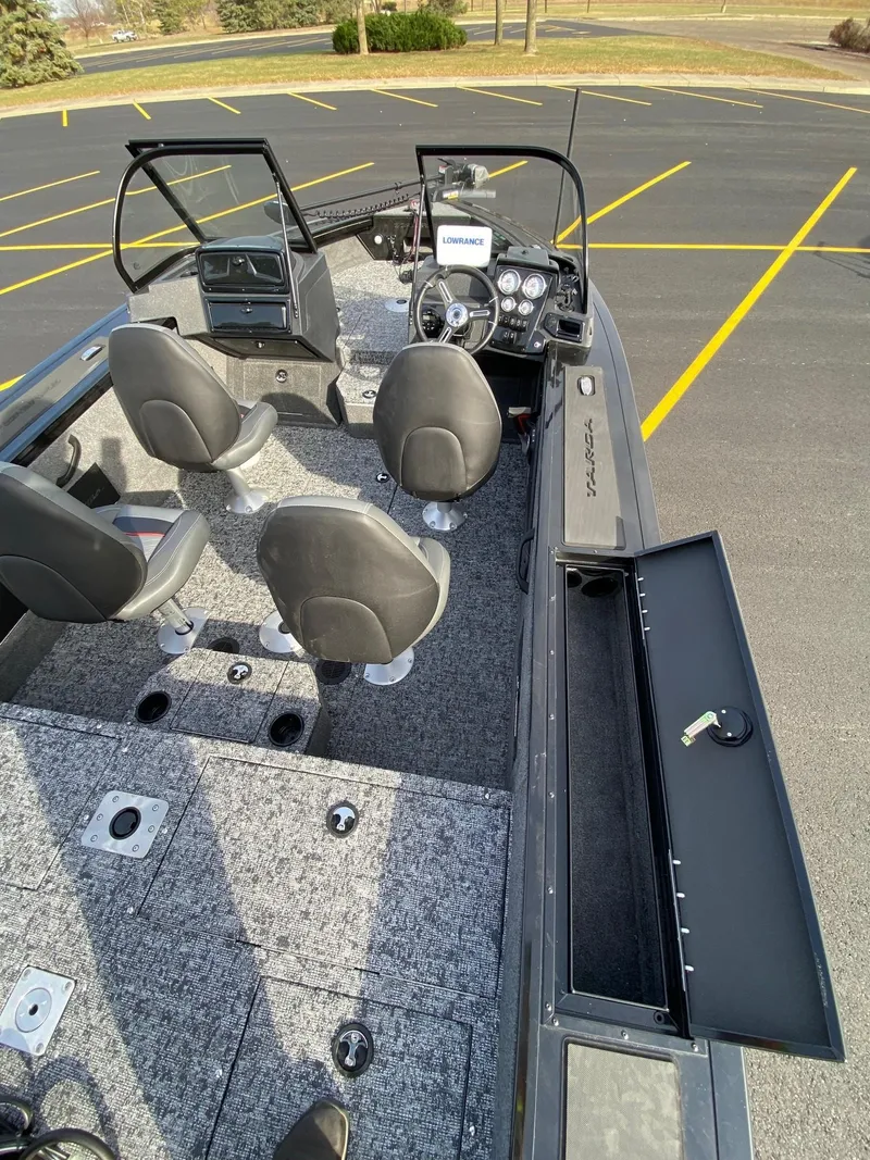 Slide: The Image of 2025 Tracker Targa V-18 WT boat interior with seating and dashboard in parking lot. - 8