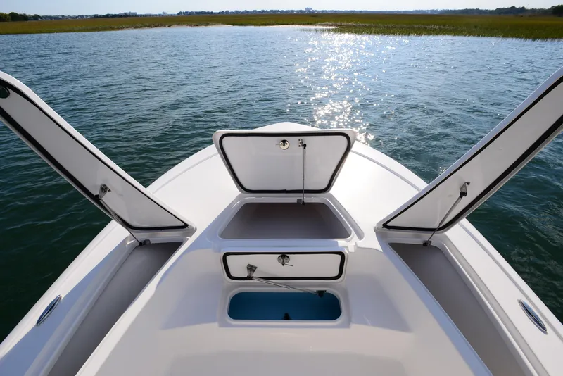 Slide: The Image of 2022 Tidewater 2110 Bay Max boat with open storage compartments on calm water. - 13