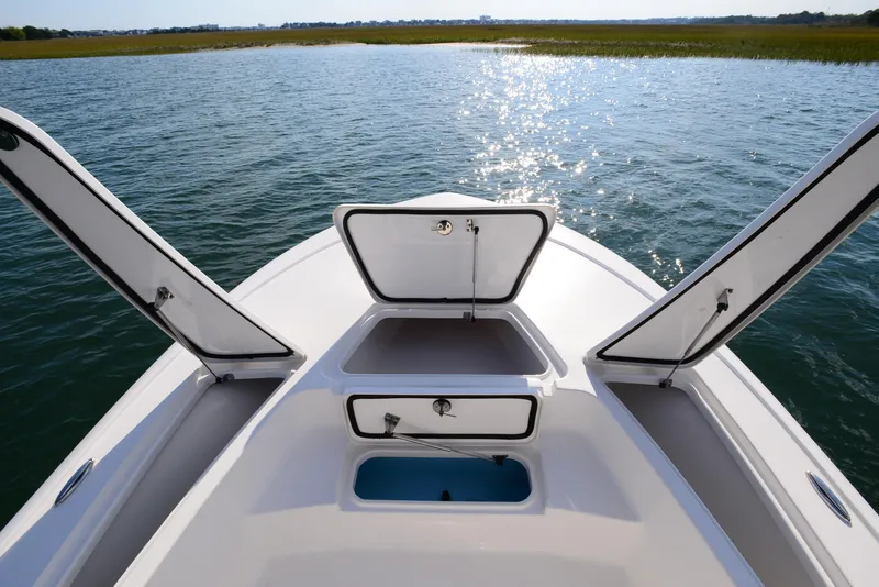 Slide: The Image of 2022 Tidewater 2110 Bay Max boat with open storage compartments on calm water. - 14