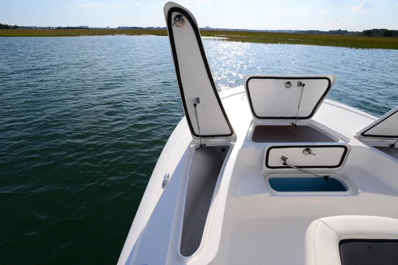 Slide: The Image of 2022 Tidewater 2110 Bay Max boat with open storage compartments on calm water. - 15