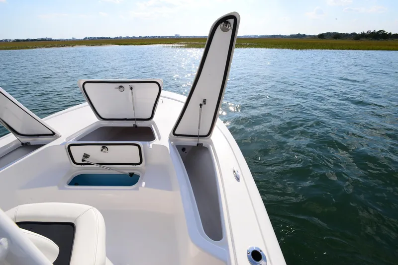 Slide: The Image of 2022 Tidewater 2110 Bay Max boat with open storage compartments on calm water. - 16