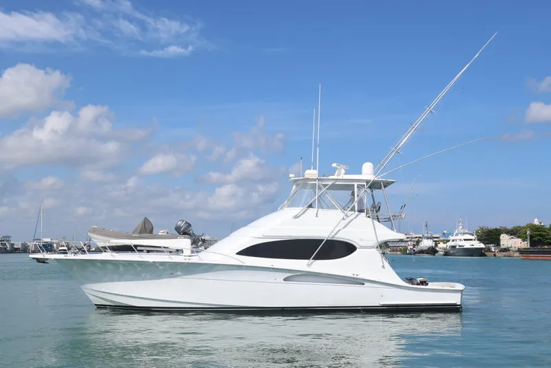 The Image of 2004 Hatteras 54 Convertible yacht on calm water under blue sky. - 0