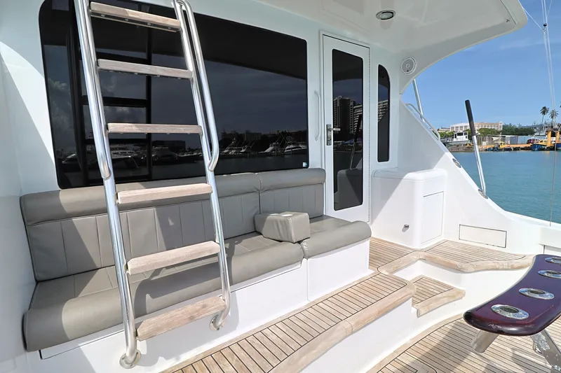 Slide: The Image of 2004 Hatteras 54 Convertible yacht deck with seating and ladder, docked by the water. - 12