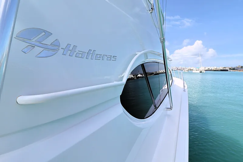 Slide: The Image of 2004 Hatteras 54 Convertible yacht on serene blue water, showcasing sleek design and branding. - 17