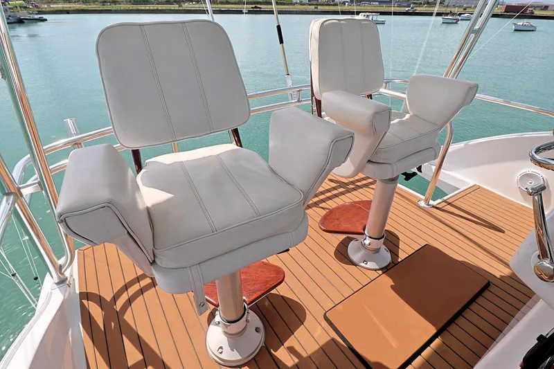 Slide: The Image of Captain's chairs on 2004 Hatteras 54 Convertible yacht deck, overlooking serene waters. - 24