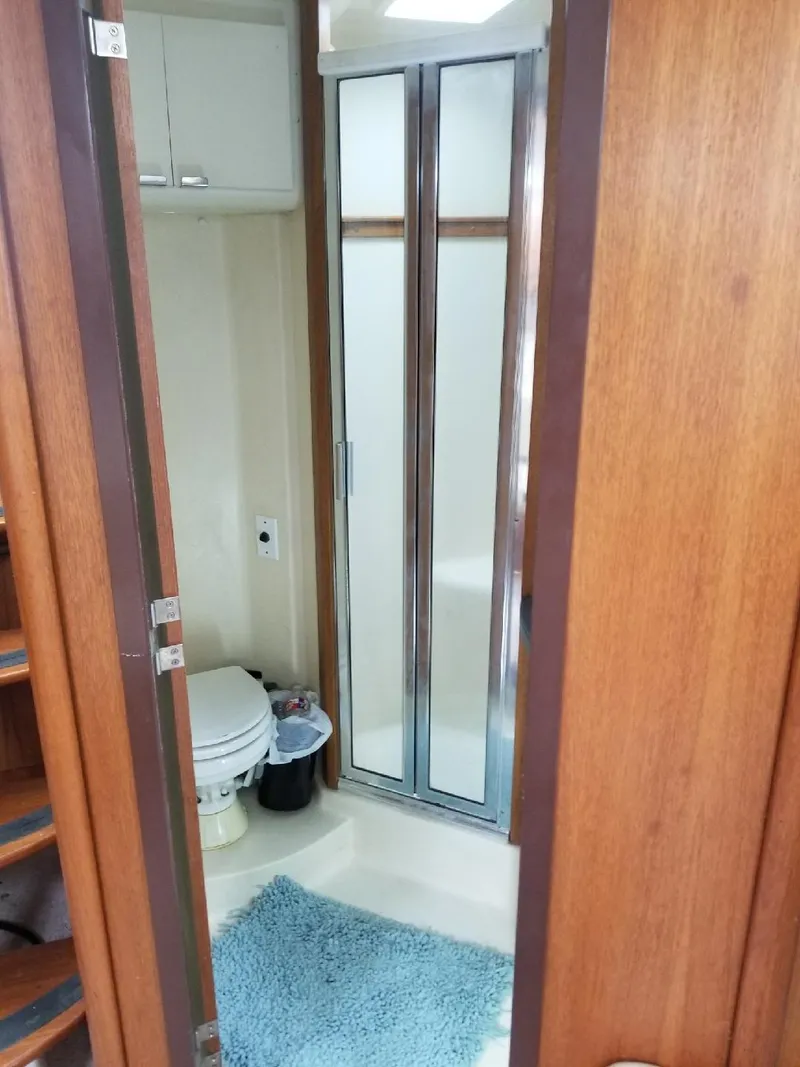 Slide: The Image of 2002 Luhrs Express boat bathroom with shower, toilet, and blue rug. - 14