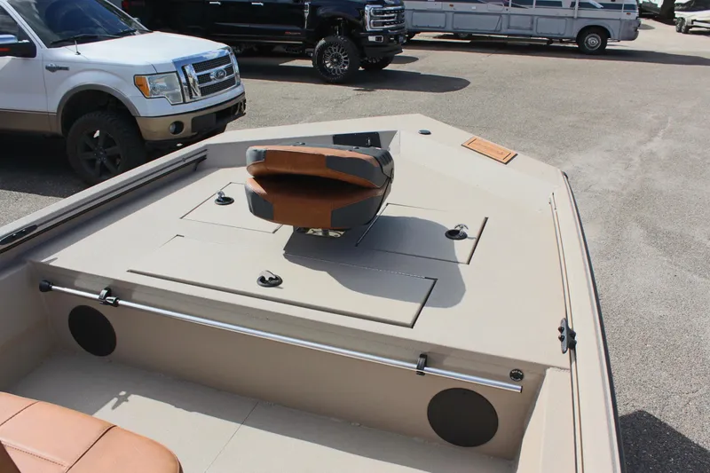 Slide: The Image of 2025 Avid 18 Rogue CC boat interior with seating and storage, parked near vehicles. - 13