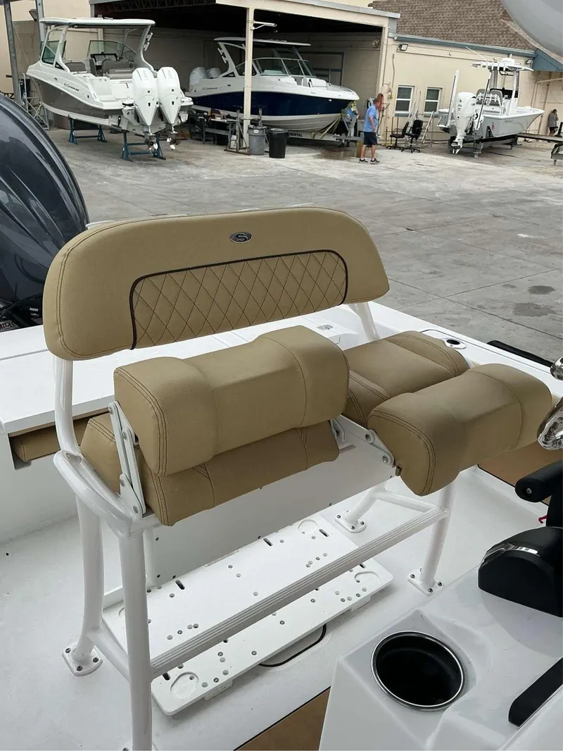 Slide: The Image of 2025 Sportsman 227 MASTERS boat seating with tan cushions in a marina setting. - 6