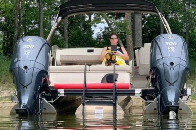 The Image of 2021 Bennington 27 QXSBWA X2 pontoon boat on trailer near a garage. - 2