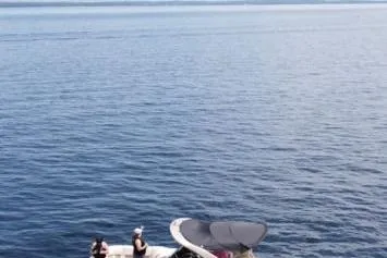 Slide: The Image of 2021 Bennington 27 QXSBWA X2 boat interior with beige seating near a lake. - 20