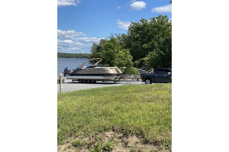 Slide: The Image of 2021 Bennington 27 QXSBWA X2 boat on trailer by a lake, surrounded by trees. - 52