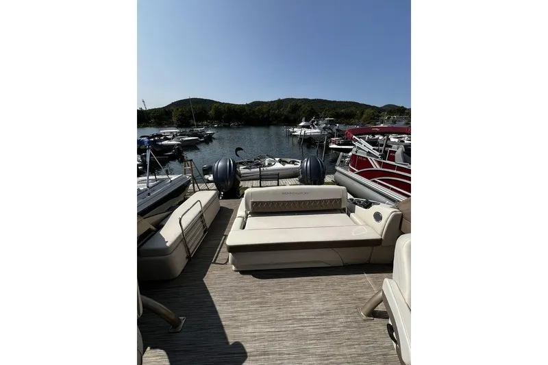 Slide: The Image of 2021 Bennington 27 QXSBWA X2 pontoon boat docked at a scenic marina. - 57