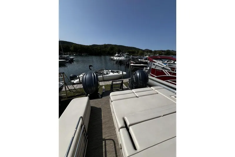 Slide: The Image of 2021 Bennington 27 QXSBWA X2 pontoon boat docked at a scenic lakeside marina. - 67