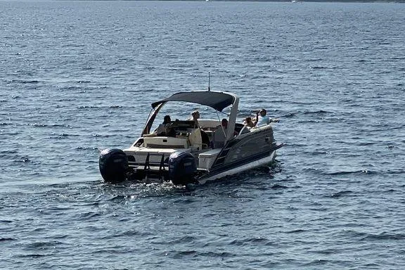 Slide: The Image of 2021 Bennington 27 QXSBWA X2 pontoon boat with beige seating and canopy, docked by a marina. - 9