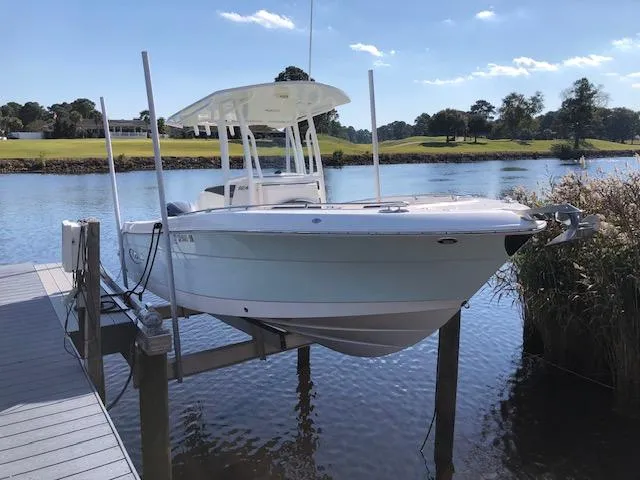 The Image of 2022 Robalo R242 Center Console boat docked on a lift by a scenic river. - 0