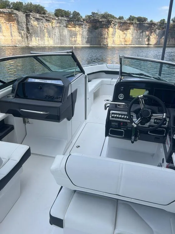 Slide: The Image of 2025 Formula 290 Bowrider interior with modern dashboard, steering, and seating by scenic cliffs. - 21