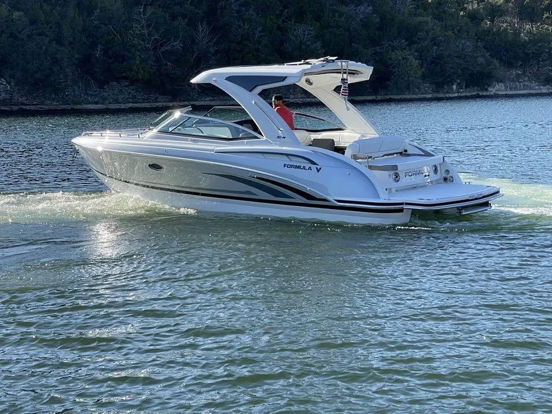 Slide: The Image of 2025 Formula 310 Bowrider cruising on a serene lake with lush greenery. - 5