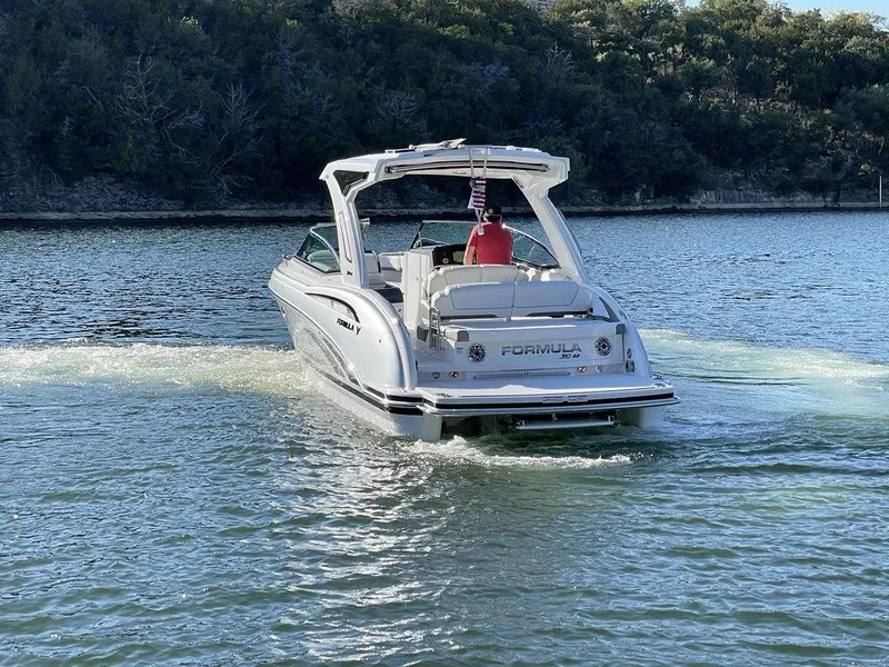 Slide: The Image of 2025 Formula 310 Bowrider cruising on a serene lake with lush forest backdrop. - 7