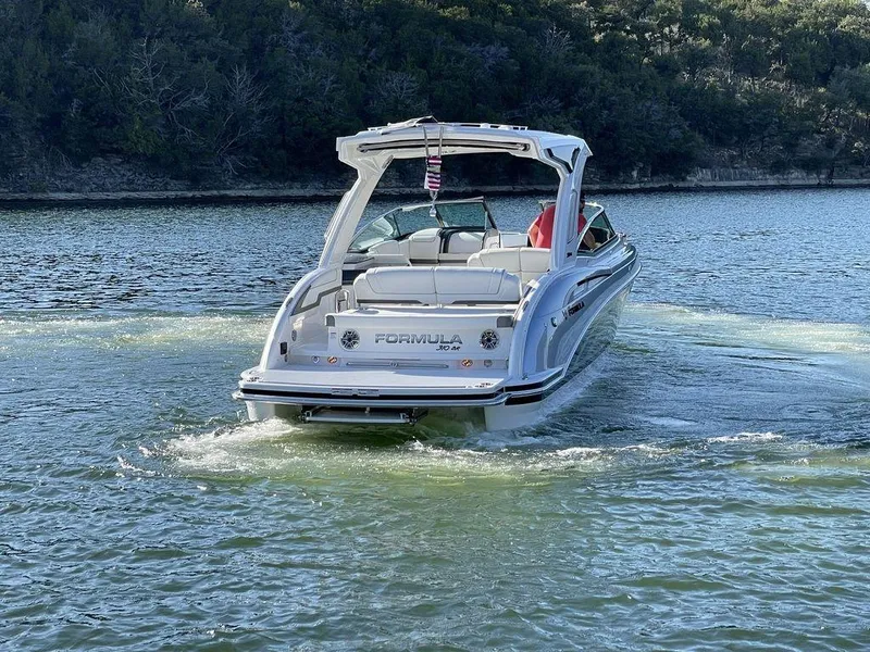 Slide: The Image of 2025 Formula 310 Bowrider cruising on a serene lake with lush greenery. - 9