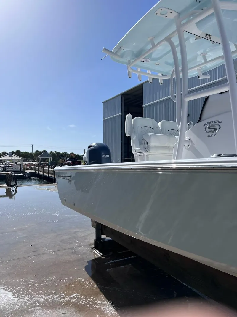 Slide: The Image of 2023 Sportsman Masters 227 Bay Boat docked near a marina under clear blue skies. - 2