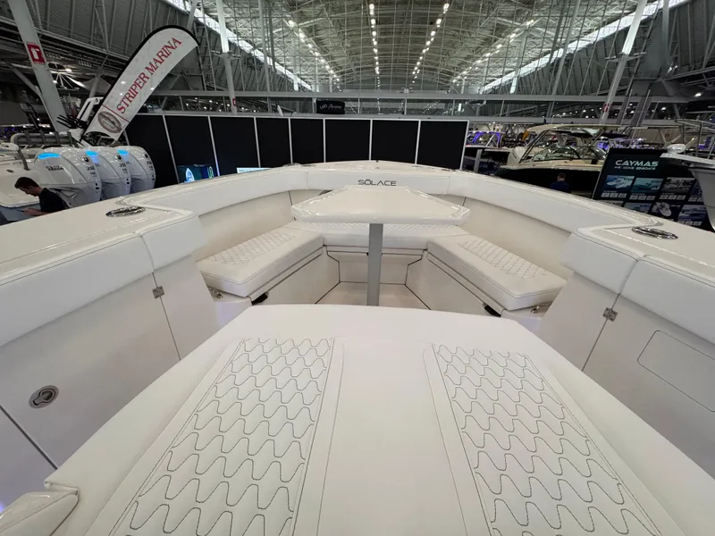 Slide: The Image of 2025 Solace 32 CS boat interior with white seating and table at a boat show. - 16