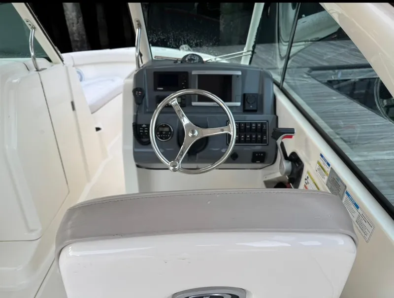 Slide: The Image of 2014 Pursuit DC 265 Dual Console boat cockpit with steering wheel and control panel. - 13