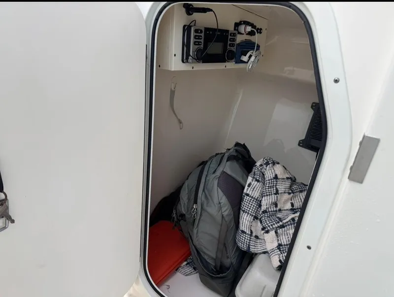Slide: The Image of Storage compartment in 2014 Pursuit DC 265 Dual Console boat with backpack and plaid jacket. - 17