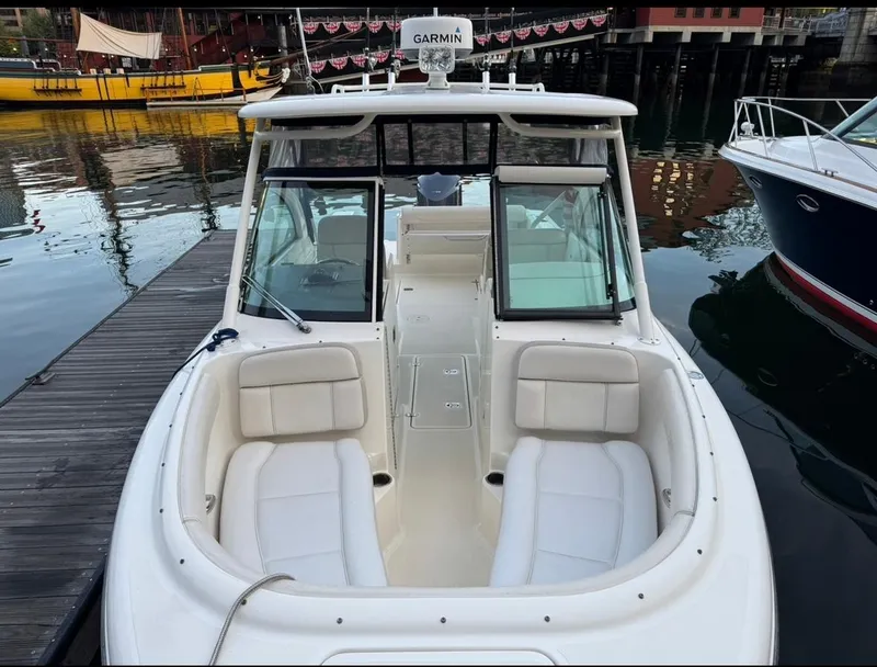 Slide: The Image of 2014 Pursuit DC 265 Dual Console boat docked, featuring spacious seating and Garmin equipment. - 18