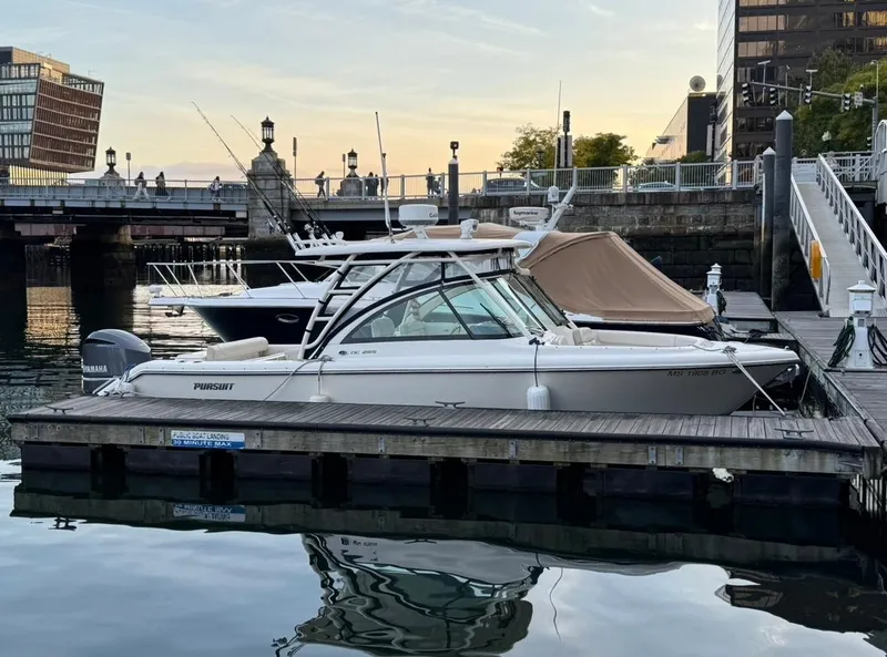 Slide: The Image of 2014 Pursuit DC 265 Dual Console boat docked at a marina during sunset. - 2