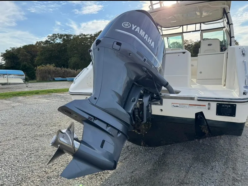 Slide: The Image of 2014 Pursuit DC 265 Dual Console with Yamaha outboard motor, parked on gravel. - 31