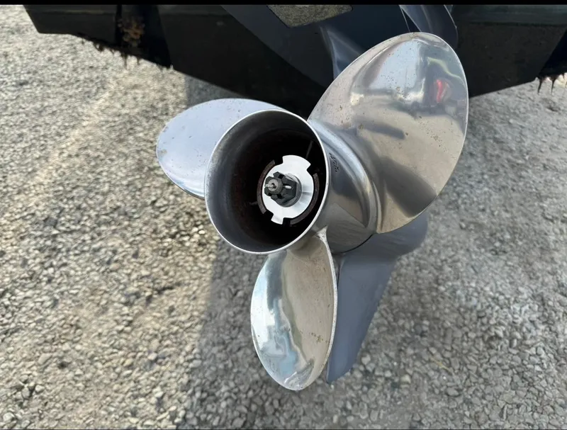 Slide: The Image of Close-up of a 2014 Pursuit DC 265 Dual Console boat propeller on gravel. - 32