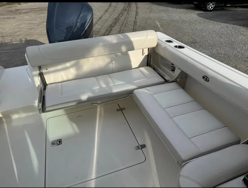 Slide: The Image of 2014 Pursuit DC 265 Dual Console boat interior with white seating and storage compartments. - 7