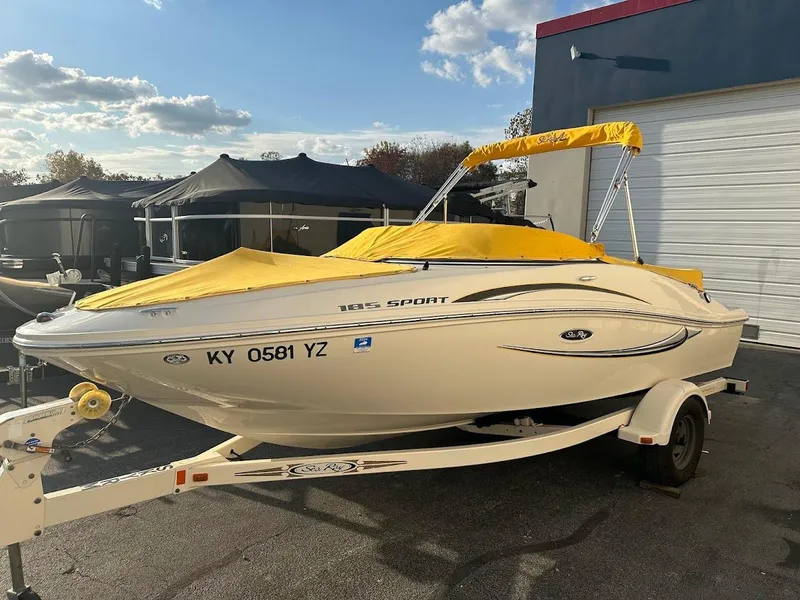 Slide: The Image of 2008 Sea Ray 185 Sport boat with yellow cover on trailer, parked outdoors. - 2