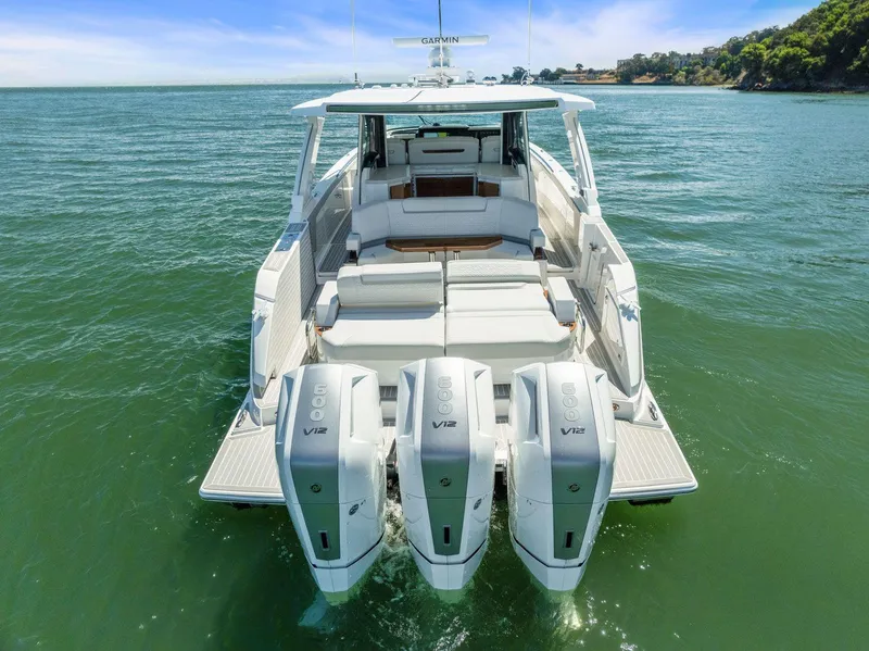 Slide: The Image of 2024 Tiara Yachts 48 LS luxury boat with triple outboard engines on open water. - 13