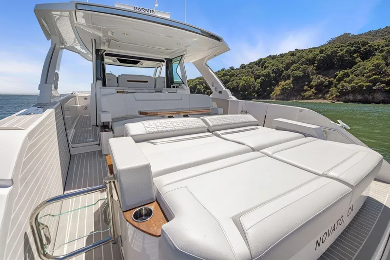 Slide: The Image of 2024 Tiara Yachts 48 LS luxury yacht with spacious deck and seating, docked by scenic shoreline. - 18