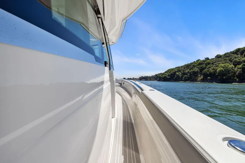 Slide: The Image of 2024 Tiara Yachts 48 LS cruising on a scenic lake with clear skies. - 29