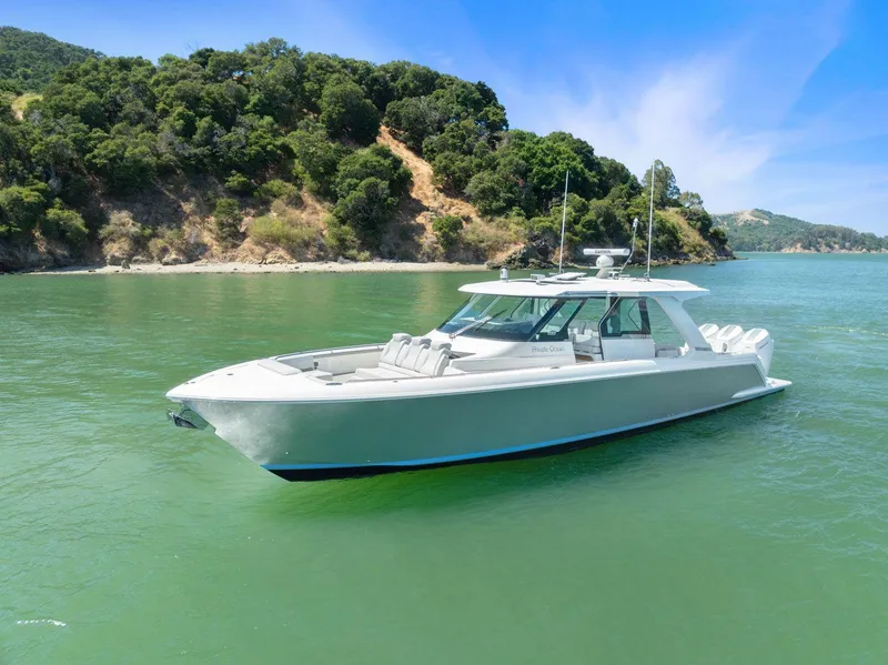 Slide: The Image of 2024 Tiara Yachts 48 LS cruising on a serene lake with lush green hills. - 5