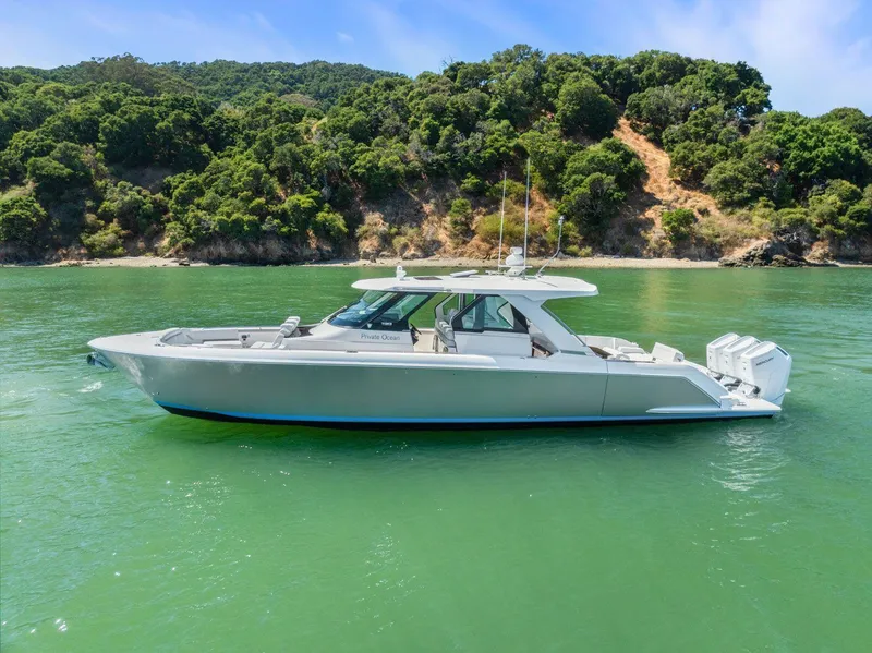 Slide: The Image of 2024 Tiara Yachts 48 LS cruising on a serene lake with lush green hills. - 6