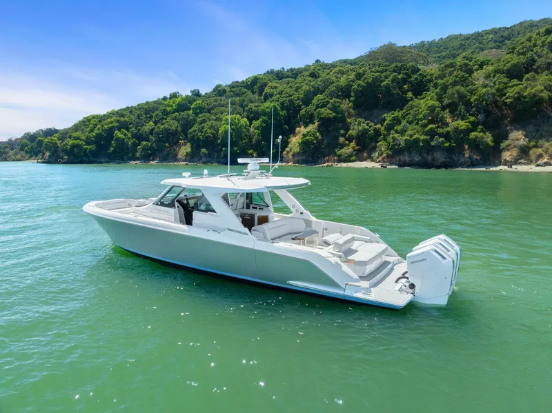 Slide: The Image of 2024 Tiara Yachts 48 LS cruising on serene green waters near lush coastline. - 7