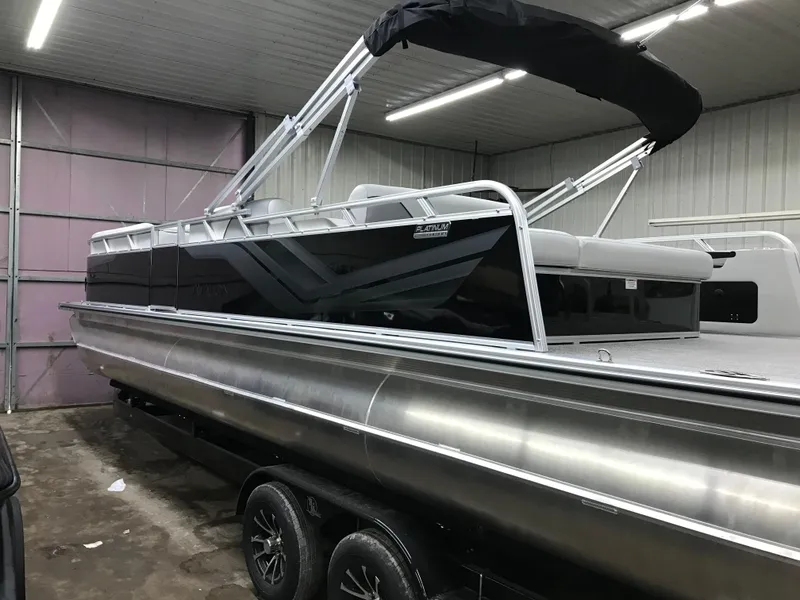 Slide: The Image of 2025 Avalon VENTURE 2585 with Mercury outboard motor, parked near a metal building. - 3