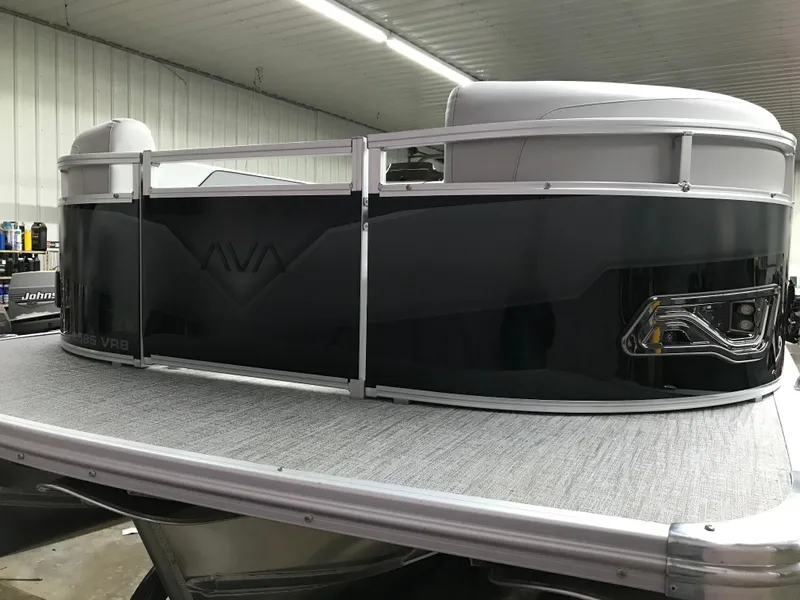 Slide: The Image of 2025 Avalon Venture 2585 with Mercury outboard motor, parked near a metal building. - 4